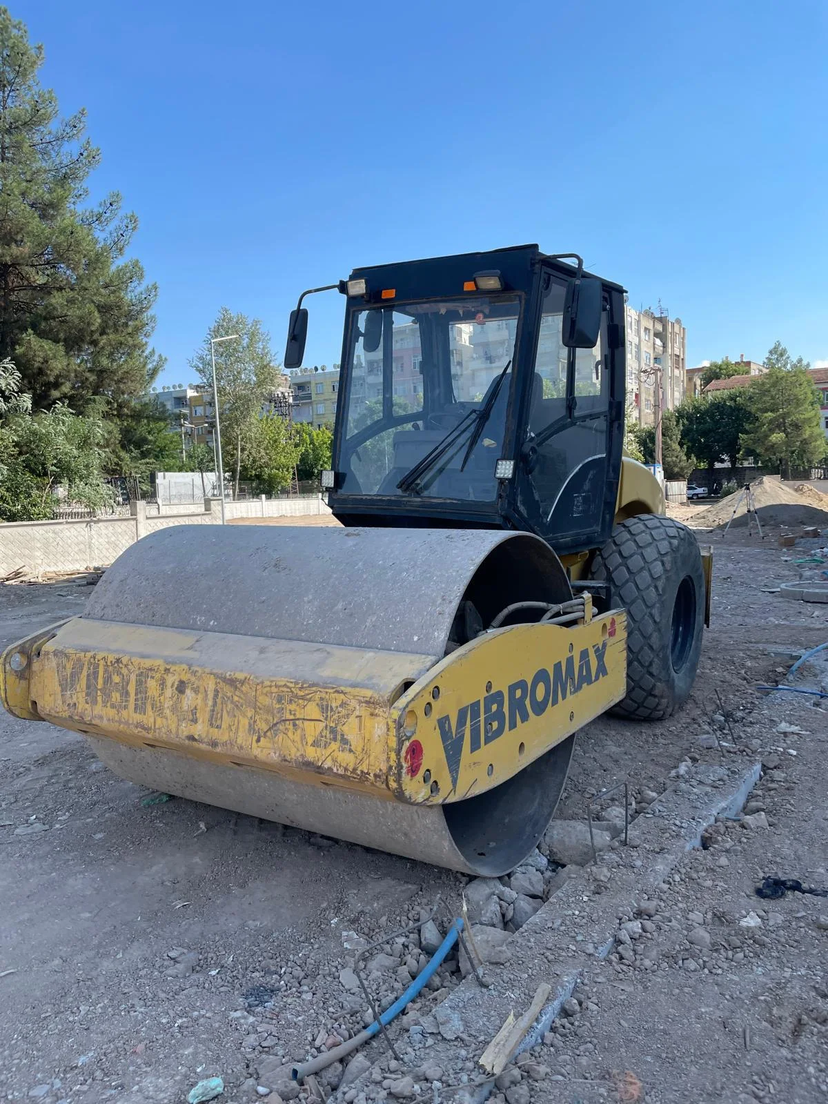 Kiralık Vibromax toprak silindiri, mıcırlı hazırlık alanında bekleyen ön görünüm; 12 ton sınıfı, 2,10 m düz tambur, kabinli.